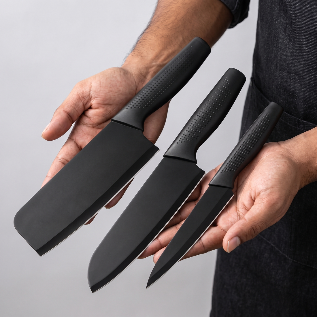 Hands holding the cleaver, santoku and utility knife side by side to show size